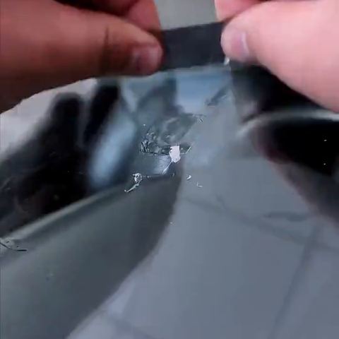 A blade scraping cured resin flat on a windscreen